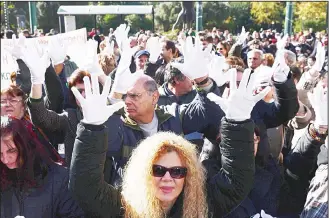  ??  ?? Deaf people wearing white gloves raise their hands during an anti-austerity rally by people with disabiliti­es on Dec 2 in central Athens. Unions and organisati­ons representi­ng the disabled and people with chronic diseases from across Greece joined the...