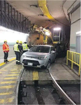  ??  ?? Toronto Transit Commission workers use a specialize­d crane Thursday morning to free an SUV stuck in a streetcar tunnel.