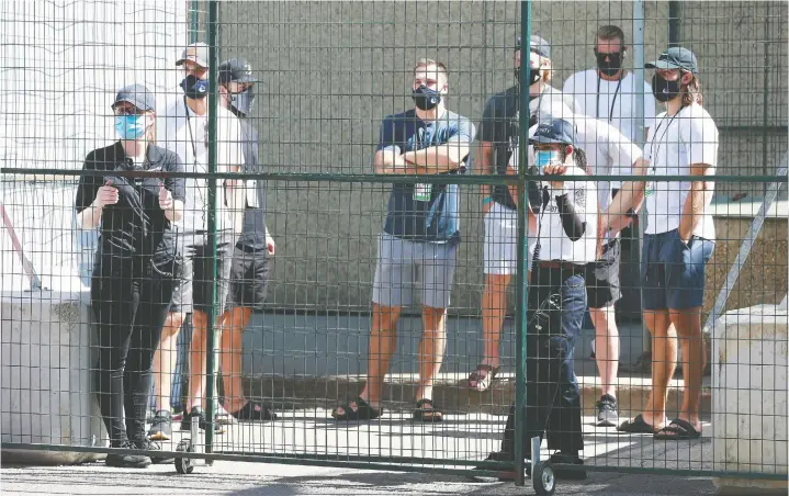  ?? GETTY IMAGES FILES ?? Vancouver Canucks players wait safely inside the bubble of protective fencing last week, as they make their way to practice at Edmonton’s Rogers Place.