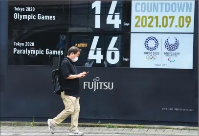  ?? The Associated Press ?? A man walks past the countdown clock for the Tokyo 2020 Olympic and Paralympic Games on Friday.