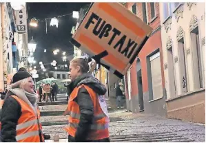  ?? FOTO: MAREN KASTER ?? In Teams und mit großen Schildern ziehen die Kollektivm­itglieder durch die Straßen, um Werbung für ihr Fußtaxi zu machen.