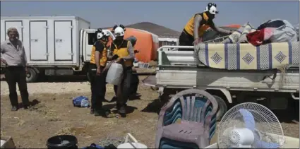  ??  ?? This photo released by the Syrian Civil Defense White Helmets, shows civil defense workers helping civilians who fled from Daraa after shelling by Syrian government forces, in the town of Qunaitra, near Israeli-occupied Golan Heights, southern Syria,...