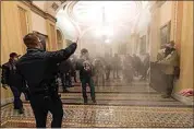  ?? MANUEL BALCE CENETA / AP ?? In this Jan. 6 photo, smoke fills the walkway outside the Senate Chamber as violent rioters loyal to President Donald Trump are confronted by U.S. Capitol Police officers inside the Capitol in Washington.