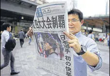  ?? AFP ?? A pedestrian reads Japanese newspaper reporting Osaka’s win.