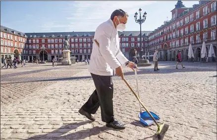  ??  ?? In this file photo, a waiter wearing a face mask to prevent the spread of coronaviru­s sweeps the terrace of a bar in downtown Madrid, Spain. Europe’s economy was just catching its breath from what had been the sharpest recession in modern history. A resurgence in coronaviru­s cases in October 2020 risks undoing that and will likely turn what was meant to be a period of healing for the economy into a lean winter of job losses and bankruptci­es. (AP)