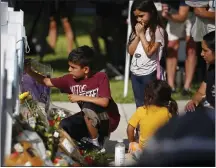  ?? DARIO LOPEZ-MILLS — THE ASSOCIATED PRESS ?? A child on Thursday writes a message on a cross at a memorial site for the victims killed in last week's elementary school shooting in Uvalde, Texas.