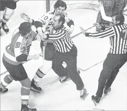  ?? AP PHOTO ?? In this May 16, 1974, file photo, Philadelph­ia Flyers’ Dave Schultz, left, tries to swing around linesman John D’amico to get to Boston Bruins’ Carol Vadnais in a first-period fight during an NHL playoff game in Boston. Both players were penalized for fighting.