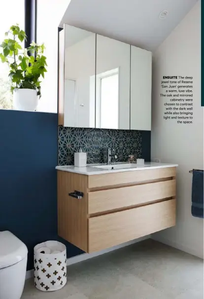  ??  ?? ENSUITE The deep jewel tone of Resene ‘San Juan’ generates
a warm, luxe vibe. The oak and mirrored
cabinetry were chosen to contrast with the dark wall while also bringing light and texture to
the space.