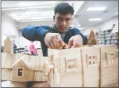  ??  ?? Student C.J. Nocon changes the battery of his haunted house, one of the multimedia haunted houses built with popsicle sticks, at McNair High School in Stockton.