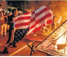  ?? SHAWN THEW / EFE ?? Un hombre lanza una bandera estadounid­ense al fuego en Washington.