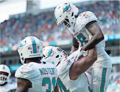  ?? ?? el tackle defensivo Christian Wilkins (94), levanta a su compañero de los Delfines De’von Achane (28) después de que anotó un touchdown en la segunda mitad del partido ante los Broncos