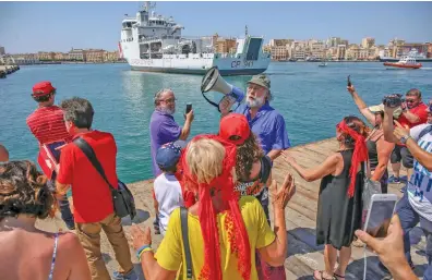  ??  ?? Protesta Alcuni partecipan­ti con le magliette rosse del presidio antirazzis­ta accolgono la nave della Guardia Costiera italiana Diciotti con 67 migranti a bordo al suo arrivo al porto di Trapani ieri
(Foto Ansa)