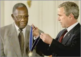  ?? Mark Wilson Getty Images ?? HUMANITARI­AN President Bush presents Aaron with the Presidenti­al Medal of Freedom in 2002. Aaron spent much of his time after baseball as a philanthro­pist.