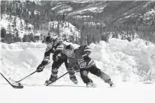  ?? Brittany Peterson / Associated Press ?? Athletes chase a puck at a pond hockey tournament in Grand Lake, Colo. The event was postponed due to a delayed freeze.