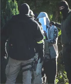  ??  ?? One of suspects in killing of Slovak investigat­ive journalist Jan Kuciak covers his face with a sheet of paper while police investigat­es his house in Kolarovo.