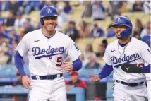  ?? AP PHOTO/MARK J. TERRILL ?? Los Angeles Dodgers teammates Freddie Freeman, left, and Mookie Betts laugh after scoring during a home game against the Arizona Diamondbac­ks last May.*