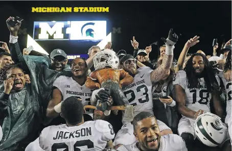  ?? GETTY IMAGES. ?? The Spartans celebrate their 14-10 win over the Wolverines with the Paul Banyun Trophy at Michigan Stadium on Saturday in Ann Arbor.