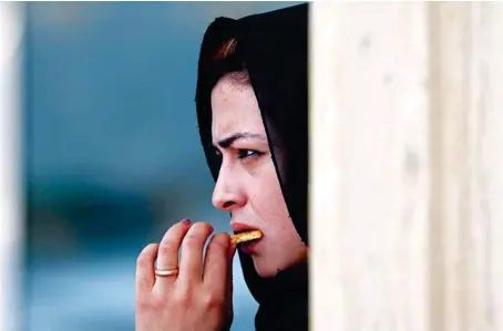  ?? AFP ?? An Afghan woman eats a biscuit in Kabul on Saturday. The UN report said the Taliban’s takeover of the country has put 20 years of ‘steady economic gains at risk.’