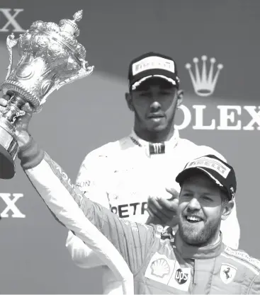  ?? ASSOCIATED PRESS ?? Ferrari driver Sebastian Vettel of Germany, right, celebrates on the podium in front of second placed Mercedes driver Lewis Hamilton of Britain after winning the British Formula One Grand Prix at the Silverston­e racetrack, Silverston­e, England.