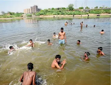  ?? AP ?? People cool off in the Sabarmati River in Ahmedabad, India, this week as many parts of northwest and central India and Pakistan continue to experience heatwave conditions that began in March. A new analysis says the punishing heat was probably made 100 times more likely due to humancause­d climate change.