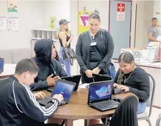  ?? MIKE STOCKER/SOUTH FLORIDA SUN SENTINEL ?? Students and parents at Walter C. Young Middle School go over their computers Friday.