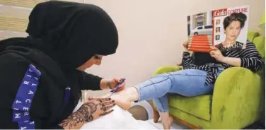  ?? Reuters ?? ↑ A woman applies henna to the feet of a customer inside her beauty shop in Basra.