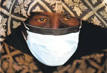  ?? PAUL SANCYA AP ?? A man waits for a bus Wednesday in Detroit. A new report by the National Academies of Sciences indicates the arrival of summer and warmer temperatur­es may not slow the spread of the coronaviru­s.