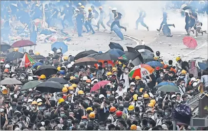  ?? [ANTHONY WALLACE/TNS] ?? Protesters run after police fired tear gas during a rally by tens of thousands of people in the streets of Hong Kong on Wednesday. More than 70 people were injured in the protests against government plans to allow extraditio­ns to China.