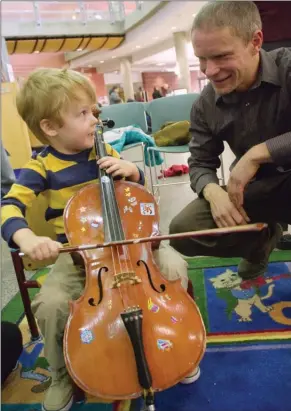  ?? BARB AGUIAR/Special to The Daily Courier ?? Isaiah Hall, 4, learns how to play the cello from Martin Kratky of the Okanagan Symphony Orchestra at the downtown Kelowna library on Saturday.