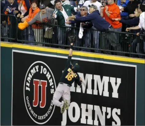  ?? AP Photo ?? Athletics right fielder Josh Reddick stretches but is unable to catch a solo home run by Detroit Tigers’ Victor Martinez, as fans reach for the ball during the seventh inning of Game 4.