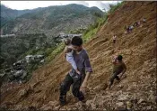  ?? JES AZNAR / THE NEW YORK TIMES ?? Survivors on Monday make their way to safety after a landslide in Itogon, northern Philippine­s, set off by Typhoon Mangkhut. About 40 to 50 miners had taken shelter in a chapel made from a converted bunkhouse when the avalanche hit.