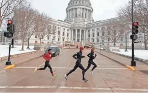  ?? MARK HOFFMAN / MILWAUKEE JOURNAL SENTINEL ?? Runners sprint past the state Capitol in Madison on Sunday. Despite concerns of possible violence at the Capitol, all was quiet.