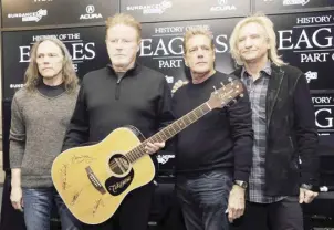  ?? ?? Members of The Eagles, from left, Timothy B. Schmit, Don Henley, Glenn Frey and Joe Walsh pose with an autographe­d guitar after a news conference at the Sundance Film Festival, Jan. 19, 2013, in Park City, Utah.