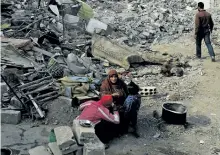  ?? DELIL SOULEIMAN/GETTY IMAGES ?? A Syrian family cooks a meal amidst the rubble in Raqqa, the former capital of Islamic State in Syria, on Friday.