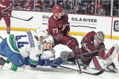  ?? DARRYL WEBB/AP ?? The Canucks’ Kyle Burroughs and Sheldon Dries and the Coyotes’ Victor Soderstrom (77) and goalie Ivan Prosvetov scramble for the puck during the third period on Thursday in Tempe.