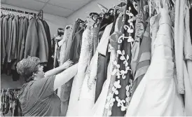  ?? [PHOTO BY SARAH PHIPPS, THE OKLAHOMAN] ?? Pivot President and CEO Kami Kuykendall looks through an assortment of dresses available at the Pivot campus for teens who hope to attend prom.