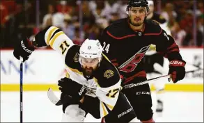  ?? Jared C. Tilton / Getty Images ?? The Bruins’ Nick Foligno and the Hurricanes’ Seth Jarvis skate during the second period in Game 7 of a first-round playoff series on Saturday.