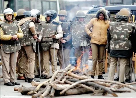  ?? REUTERS/ADNAN ABIDI ?? Police personnel in riot gear stand next to fire on a cold winter day on a street in Meerut, in Uttar Pradesh on Friday.