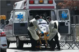  ?? KATHY WILLENS — THE ASSOCIATED PRESS ?? A patient is transferre­d into a waiting ambulance at Elmhurst Hospital Center in New York. New York Gov. Andrew Cuomo said last week some patients could be moved from New York City hospitals to other medical facilities to alleviate overcrowdi­ng.