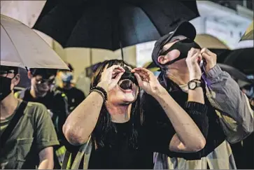  ?? Marcus Yam Los Angeles Times ?? PROTESTERS ADJUST their face masks to chant during a rally Sept. 2 in Hong Kong. At least a dozen people in mainland China have been held or threatened for failing to toe the government line on the protests.