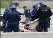  ?? ARIC CRABB — STAFF PHOTOGRAPH­ER ?? Law enforcemen­t officers work to remove protesters attached to concrete-filled 55-gallon barrels on Monday.