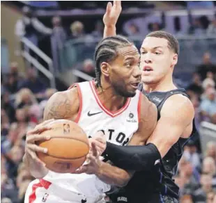  ??  ?? Kawhi Leonard, de Toronto, protege el balón frente a la defensa de Aaron Gordon, de Orlando, en acción del partido de ayer en el baloncesto de la NBA.