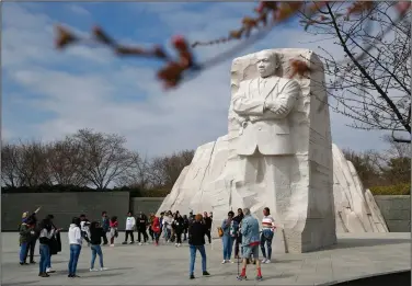  ?? (AP/Patrick Semansky) ?? Visitors gather at the Martin Luther King Jr. Memorial as cherry blossoms begin to show signs of blooming Thursday in Washington. City health officials recommende­d Wednesday that all “nonessenti­al mass gatherings, including conference­s and convention­s,” be postponed or canceled through the end of March, a move that could imperil the popular Cherry Blossom Festival.