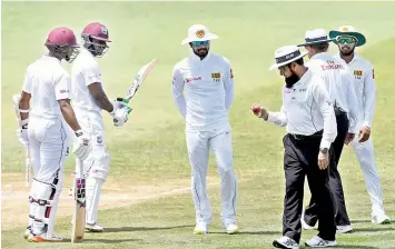  ??  ?? Sri Lanka captain Dinesh Chandimal (centre) looks on as umpire Aleem Dar inspects the ball on day 3 of their second Test against the West Indies at Daren Sammy cricket ground in Gros Islet, St. Lucia, on Saturday. — AFP