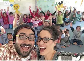  ??  ?? SMILES ALL AROUND: Ali and Mina ( above) pose along with children at the refugee camp in Jordan; ( right) teaching autistic children new skills and fun tricks
