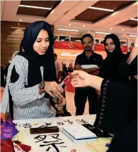  ??  ?? Amna Darmaki (not in photo) presents a bookmark with Japanese characters to a visitor at the SIBF.