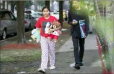  ?? PHOTOS BY ERIN HOOLEY — CHICAGO TRIBUNE VIA AP ?? People carry things away from the scene of a fire that killed several people including multiple children Sunday in Chicago. The cause of the blaze hasn’t been determined.