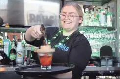  ?? Jeremy stewart ?? Bartender Sophia Ferguson uses a torch lighter to burn flavord wood chips over the top of The Locomotive, one of the signature cocktails available at The Rails at Rockmart.