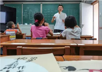  ??  ?? Children attend a class in a school in Baijiaoci on September 9