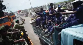  ?? PHIL MOORE/AFP/GETTY IMAGES ?? M23 rebels, left, pass a truck of police officers Saturday as they withdraw from Goma in the Democratic Republic of Congo. The rebels left after a 12-day occupation of the city.